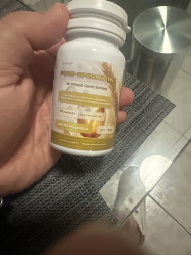 Reviewer's hand holding a white bottle labeled Pure-Spermidine, distinct from the Nutriop Berberine product.