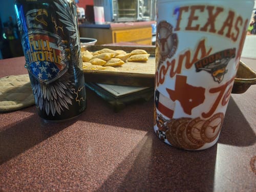Customer's Universal Buddy Texas Longhorns sticker can cooler next to a drink on a kitchen counter.