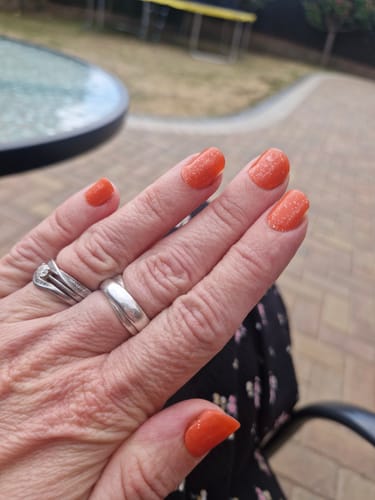 Customer's hand showing long-lasting Coral Fizz nail gels applied to natural nails.