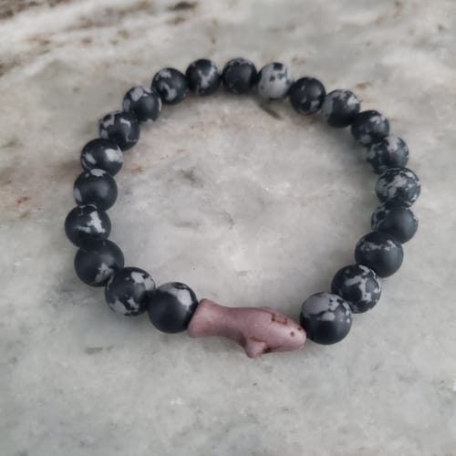 Customer's grey stone Voyage Bracelet with a shark-shaped charm centered against a light surface.