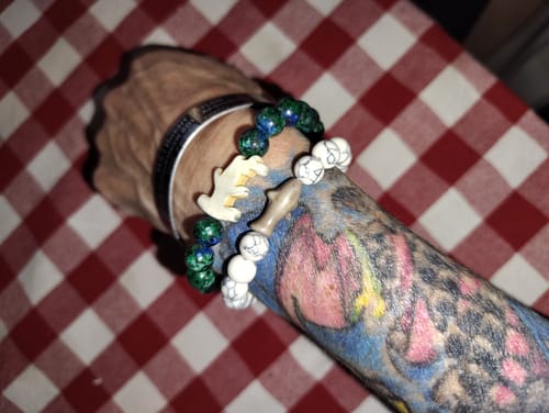 Customer's Voyage Bracelet featuring a shark charm, worn on a tattooed arm alongside other beaded bracelets.