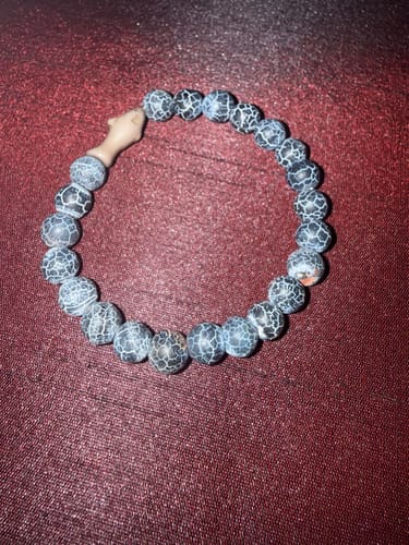 Customer's gray Voyage Bracelet with a tan shark bead, resting on a dark surface.