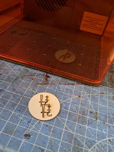 Customer's AtomStack Atelier laser engraver with a circular wooden cutout featuring a precise engraved design.