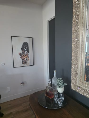 Customer's framed dog pearl art project hanging on a white wall in a living room.