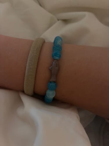 Customer's blue beaded Voyage Bracelet with a shark charm worn on their wrist