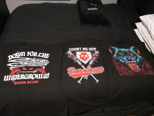 Customer's BATTLES T-SHIRT collection spread out on a bed, showing three different black graphic designs.