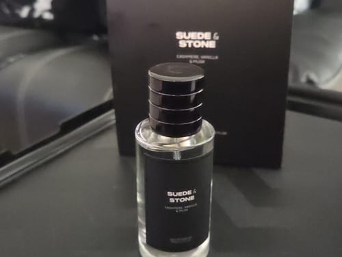 Customer's Suede & Stone Eau de Parfum bottle standing in front of its matching black product box.