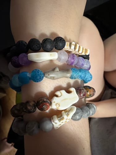 Customer's arm wearing five stacked Voyage Bracelets with various animal charms and colorful beaded designs.