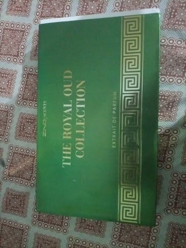 Customer's green box of The Royal Oud Collection featuring geometric patterns, placed on a patterned surface.