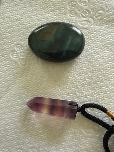 Reviewer's Labradorite Moonstone and fluorite pendant from VIP Crystal Club on a textured white surface.