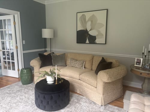 Customer's Whispering Petals canvas art hanging above a tan sofa in a cozy, decorated living room.
