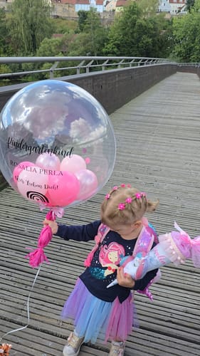 Customer's personalized BALLOONIZER balloon with pink accents held by a child on a bridge