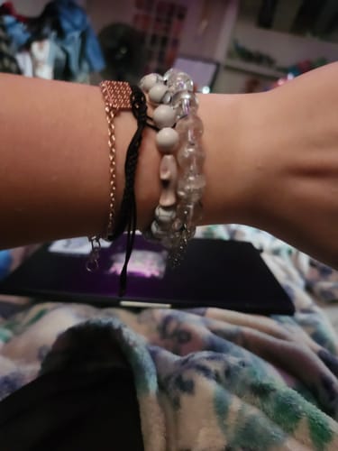 Customer's wrist wearing the Voyage Bracelet alongside other beaded and string bracelets.