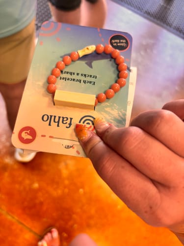 Customer's orange Voyage Bracelet on its shark-themed display card