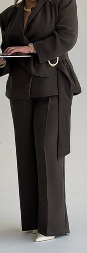 Reviewer wearing dark brown Suiting Pleated Wide-Leg Pants and matching blazer while using a laptop.