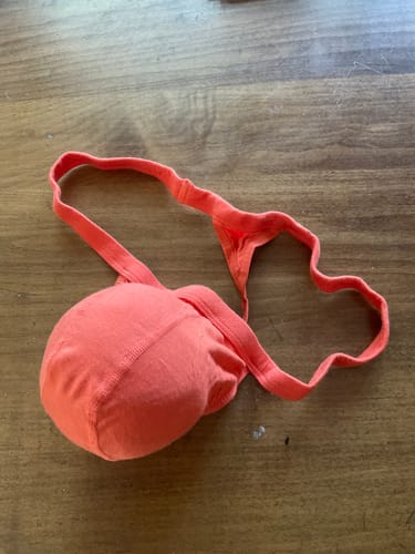 Reviewer's orange Modal thong on a wooden table, showing the supportive pouch and thin waistband.