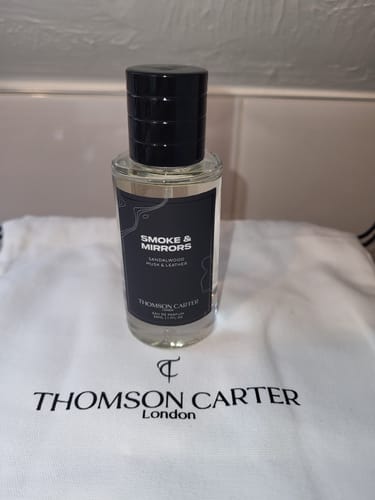 Customer's Smoke & Mirrors perfume bottle standing on a branded Thomson Carter white fabric bag.
