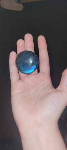 Reviewer's hand holding a smooth, round blue and dark crystal from the VIP Crystal Club.
