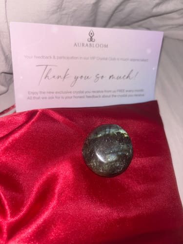 Customer's VIP Crystal Club labradorite piece on red fabric, next to a thank you note from the brand.
