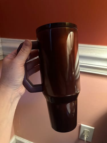 Customer's hand holding a dark brown Thicc Buddy 40oz mug.