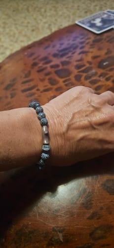 Customer's dark beaded Voyage Bracelet with a shark charm worn on their wrist.