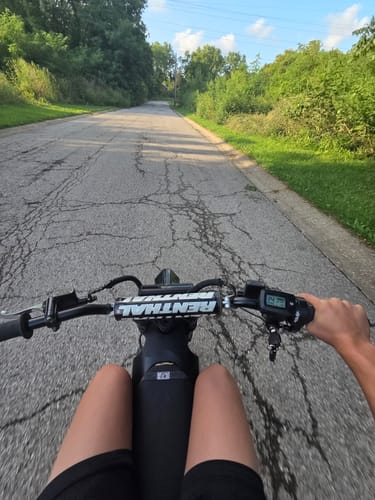 Reviewer's perspective riding a bike with the Tuttio Soleil 01 throttle and digital display visible on the handlebars.