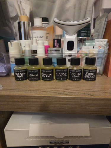 Customer's Discovery Set of six small glass fragrance oil bottles arranged in a clear storage bin on a vanity.