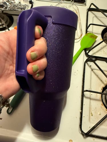 Customer's purple glitz Thicc Buddy 40oz mug held in a person's hand in a kitchen.