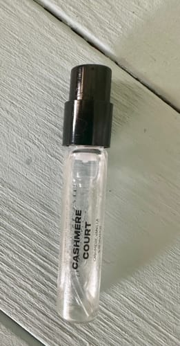 Customer's Cashmere Court Eau de Parfum sample vial, showing the clear glass bottle on a light, slatted surface.
