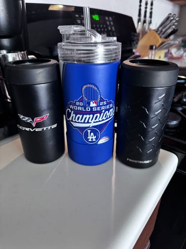 Customer's blue Universal XL tumbler with a drinking lid, flanked by two black insulated drink holders on a counter.