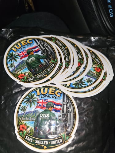 Customer's pile of round custom vinyl stickers featuring an illustration of a worker, palm trees, and a flag.
