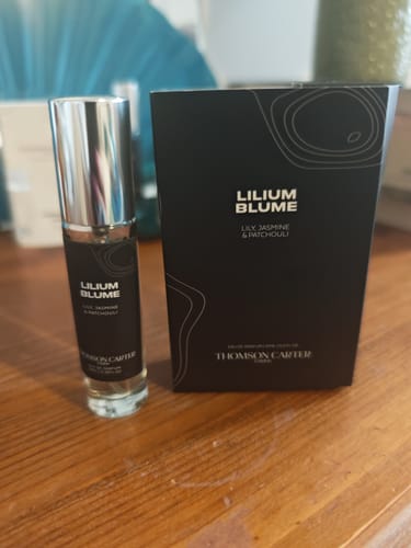 Customer's Lilium Blume perfume bottle next to its sleek black box on a wooden surface.