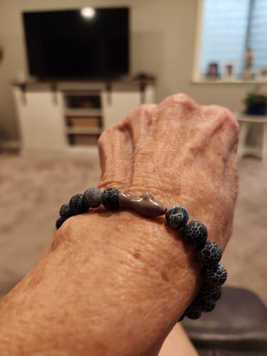 Customer's gray Voyage Bracelet with a shark charm worn on their wrist.