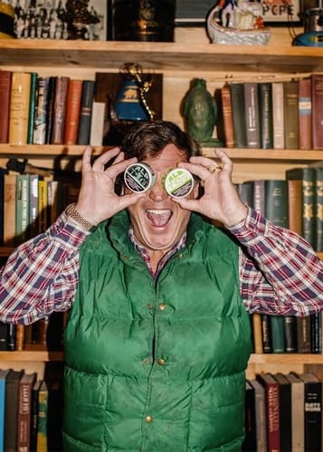 Reviewer holds two circular Thank You Card pouches over their eyes in front of a wooden bookshelf.