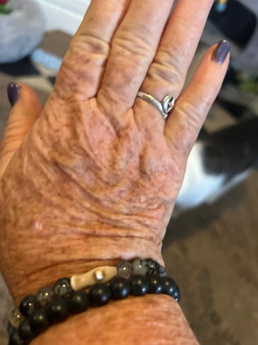 Customer's wrist wearing two dark-beaded Voyage Bracelets, one with a prominent beige shark charm.