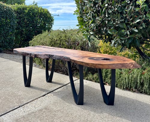 Customer's handcrafted Udo bench legs supporting a rustic wood slab bench outdoors on a patio.