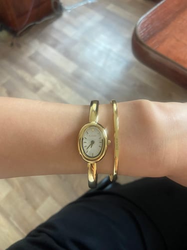Customer's Diana Petite Gold White watch and matching gold bangle worn on a wrist.