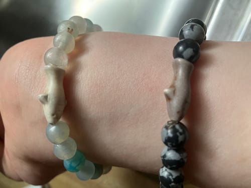 Customer's wrist wearing two Voyage Bracelets, one with gray and white stones, and one with black and gray patterns.
