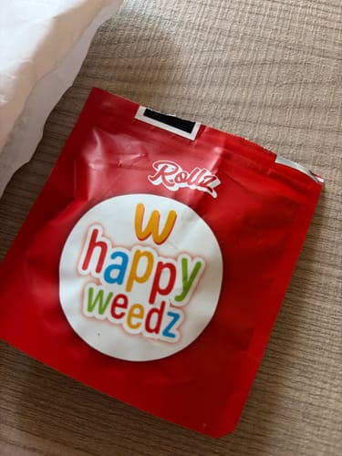 Customer's bright red Happy Weedz THCA flower pouch sitting on a textured surface.