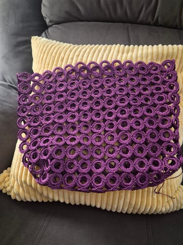Customer's purple circular crochet shell for the Garden Bee Crochet Bag Kit, resting on a textured cushion.