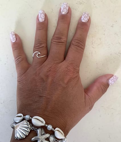 Kundenhand mit aufgetragenen UV Gel Wild Blush Nagelfolien im hellen Leo-Muster-Design.