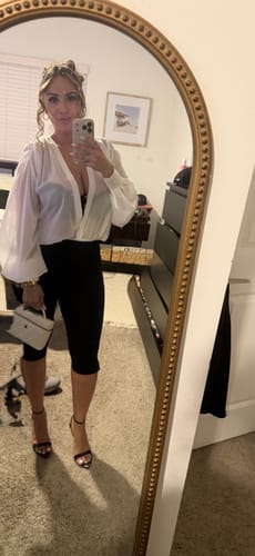 Customer's chiffon bodysuit on a person standing in front of a mirror, worn with dark bottoms and high heels.