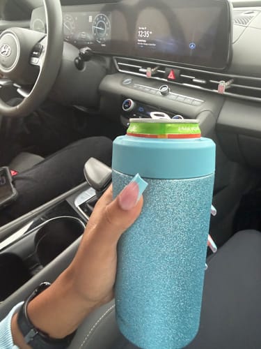 Customer's hand holding a light blue sparkly Universal Buddy can cooler inside a vehicle.
