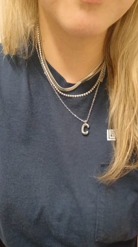 Customer's Chelsea Herringbone Necklace worn as part of a layered silver-toned necklace set on a person.