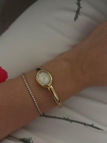 Reviewer's wrist wearing an elegant gold Ava Petite Gold White Bracelet next to a sparkling delicate bracelet.