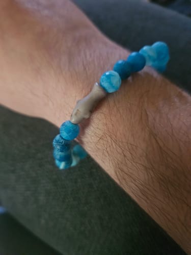 Customer's blue Voyage Bracelet with a shark charm worn on their wrist.