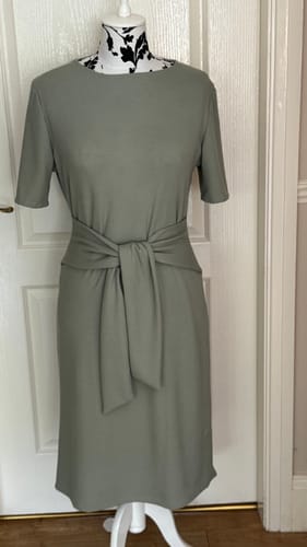 Reviewer's sage green knit jersey dress, featuring a front tie detail, displayed on a mannequin.