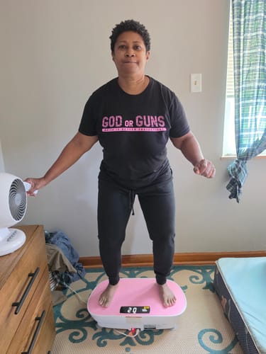Customer's pink CV30 Pro vibration plate in use with a person standing on it in a home setting.