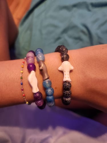 Reviewer's arm wearing three beaded Voyage Bracelets featuring animal charms.