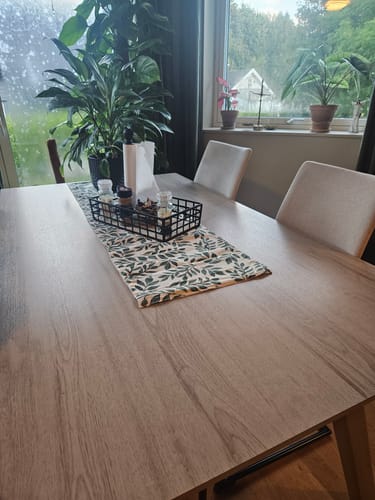 Reviewer's spisebord dekket med Oak minimal kontaktplast i eiketre-look med en bordløper og dekor.
